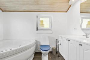 ein Badezimmer mit einer weißen Badewanne und einer blauen Toilette in der Unterkunft 8842 Glesborg - Marie Nielsens Vej 5 in Glesborg + 17 Fotos