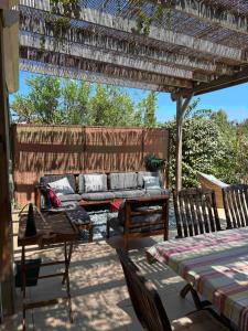 une terrasse avec un canapé et des chaises sous une pergola dans l'établissement Maison à Lumio Marine de Sant Ambroggio en Balagne, Haute Corse / Holiday House Corsica, à Lumio 9 autres photos