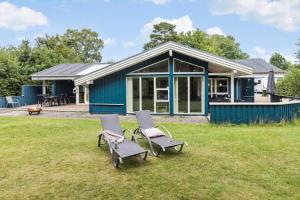 a blue house with two chairs in the grass at 8522-Grenaa-Nobilisvej-15 in Grenå