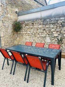 a ping pong table with four chairs in front of a stone wall at Casa Victoria in Ruelle-sur-Touvre