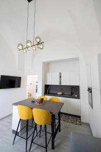サン・ヴィート・デイ・ノルマンニにあるCasa Vacanze Centro Storicoのキッチン(黒いテーブル、黄色い椅子付)