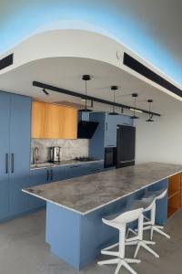 una cocina con una encimera grande con 2 taburetes blancos en Penthouse Yacht, en Netanya 34 fotos más