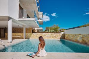a woman in a white dress sitting next to a swimming pool at Luxury apartment Tamana Blue - by Welcomely in Jávea