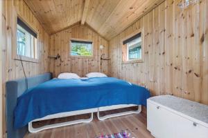 a bedroom with a blue bed in a wooden wall at 84256-Ronde-Strandvejen-108 in Rønde