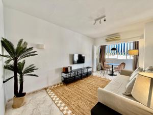 un soggiorno con divano e palma di The Suit III Marbella Center - EaW Homes a Marbella