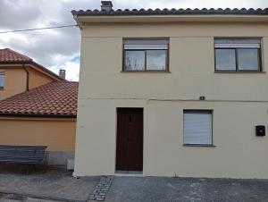a white house with a door and a bench at La Casa de Pepe in Muros de Nalón