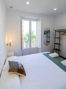 カディスにあるApartamentos La Cruz Verdeの大きな窓のある大きな白いベッドのある寝室