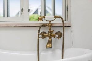 a bathroom sink with a brass faucet next to a window at 1480-N-Liseleje-Hellevej-9 in Liseleje +28 photos