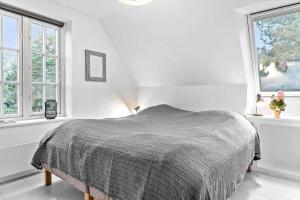 a white bedroom with a bed and two windows at 1539-Liseleje-Skippervej-3 in Liseleje