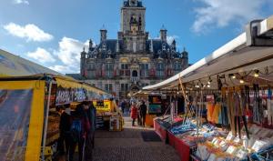 a market in front of a large building with a clock tower at Hotel La Noire - Delft City Centre in Delft