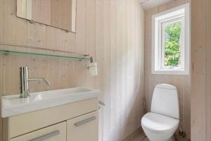 a bathroom with a toilet and a sink and a window at 1650-Asserbo-Fyrrevangen-17 in Asserbo +13 photos
