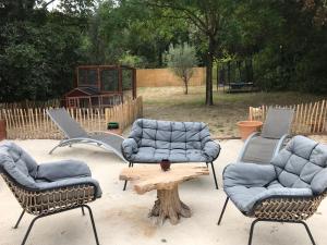three chairs and a table with a couch on a patio at Maison belle-vie in Corconne