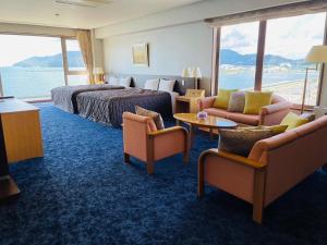 a hotel room with a bed and a couch and chairs at Shikisainoyado Hanatsubaki in Obama
