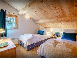 two beds in a room with a wooden ceiling at Chalet Joux Verte - OVO Network in Les Gets +17 photos
