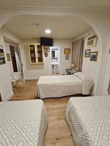 ein Hotelzimmer mit drei Betten und einem Fernseher in der Unterkunft Alojamiento la Casa del Brigadier in Cerro Muriano