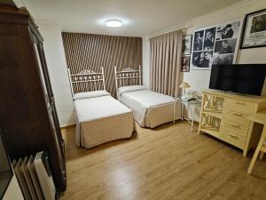a small room with two beds and a television at Alojamiento la Casa del Brigadier in Cerro Muriano +4 photos