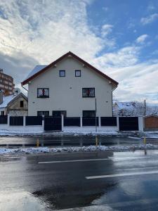 a white building with a fence in front of a street at Casa de Caramida in Braşov