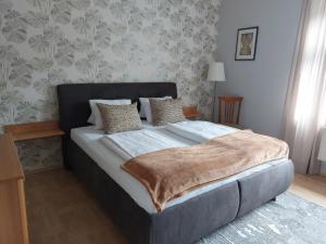 a bedroom with a large bed with a blanket on it at Apartmán Rainbow se zahradou, bazénem a parkováním in Karlovy Vary