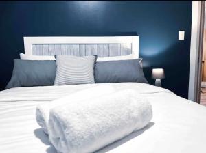 a bedroom with a white bed with a blue wall at Luxurious 2 bedroom Apartment! in Centurion