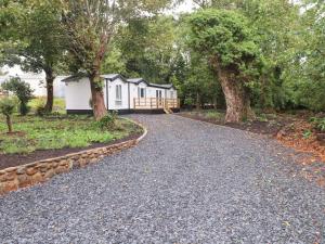 a gravel road leading to a house with trees at The Chalet at Tyn Lon in Pwllheli