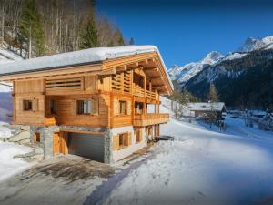 Eine Blockhütte im Schnee mit Bergen im Hintergrund in der Unterkunft Chalet Angelia - OVO Network in Le Grand-Bornand