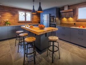 eine Küche mit blauen Schränken und eine Insel mit Barhockern in der Unterkunft Chalet Angelia - OVO Network in Le Grand-Bornand