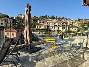 Un patio con una mesa y sillas y una sombrilla. en Villa Catocce - Beautiful New Apartments with Parking - by HOST4U, en Imperia