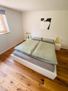 a large bed in a bedroom with a wooden floor at Helle Ferienwohnung Zum Relaxen in Horgenzell