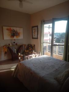 a bedroom with a bed and a large window at Apartamento Piúma in Piúma