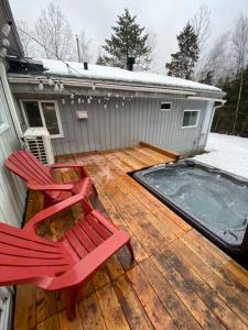 two red chairs sitting on a deck with a hot tub at Spa and River - Le Petit Cocon in Chateau Richer