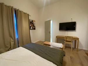 a bedroom with a bed and a desk with a television at Tropical Oasis Hôtel in Vouvouni