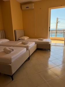 two beds in a room with a large window at k&k apartament in Sarandë