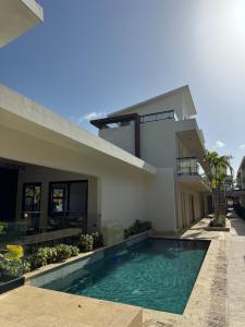 a house with a swimming pool in front of it at New & Chic 3-Bedroom Penthouse, Punta Cana, Pool-BBQ-Beach Access-Private Rooftop-Padel y Sports amenities in Punta Cana