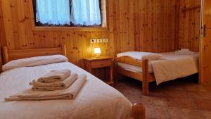a bedroom with two beds and a lamp and a window at Lavarone & Folgaria Residence in Lavarone