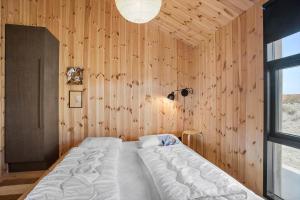 Un dormitorio con una cama en una pared de madera. en BL1436-Blokhus-Mollevej-13, en Blokhus