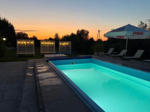 a swimming pool with a sunset in the background at Nad Starą Nidą *** in Pińczów