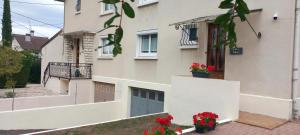 ein weißes Haus mit roten Blumen in einem Hof in der Unterkunft Maison Cosy avec Terrasse à Vallenay in Vallenay