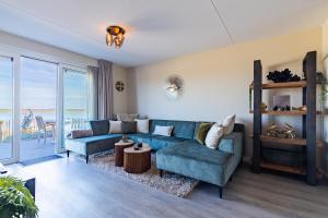 a living room with a blue couch and a table at Vakantiewoning aan het strand 'Somaris' - met tuin en terras - Vista Maris - Nr 50 in Sint Annaland