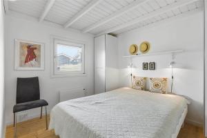 una camera da letto bianca con un letto e una sedia di BL1555-Blokhus-Egebaeksvej-17 a Blokhus