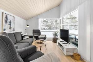 a living room with a couch and a tv at BL1739-Blokhus-Bag-Hojen-47 in Blokhus