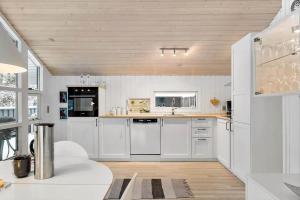 a kitchen with white cabinets and a wooden ceiling at BL1739-Blokhus-Bag-Hojen-47 in Blokhus
