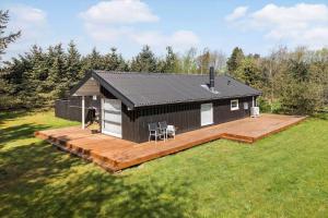 a small black and white cabin with a wooden deck at BL1739-Blokhus-Bag-Hojen-47 in Blokhus