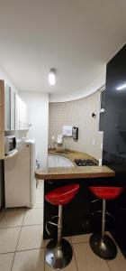 a kitchen with two red stools at a counter at Tranquilidade e Vista Panorâmica - Nova Lima in Nova Lima