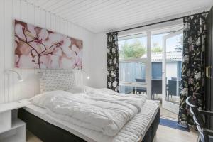 a bed in a bedroom with a large window at BL1487-Saltum-Brune-Banke-7 in Saltum