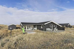 a black house with a deck in a field at BL1455-Blokhus-Pirupshvarrekrogen-6 in Blokhus
