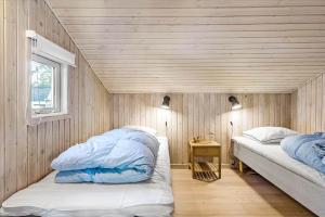 two beds in a room with a wooden wall at BL1361-Saltum-Jaerens-Rev-Sydvest-8 in Saltum