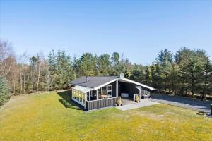 a small house with a black roof on a grass field at BL1361-Saltum-Jaerens-Rev-Sydvest-8 in Saltum