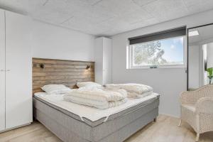 ein Schlafzimmer mit einem großen Bett mit Fenster in der Unterkunft BL1405 Blokhus - Sletten 12 in Blokhus