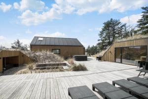 eine Holzterrasse mit Bänken und ein Gebäude in der Unterkunft BL1405 Blokhus - Sletten 12 in Blokhus