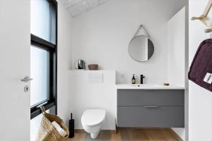 un bagno con un water, un lavandino e uno specchio di BL1489-Blokhus-Paa-Bakken-8-B a Blokhus Altre 22 foto